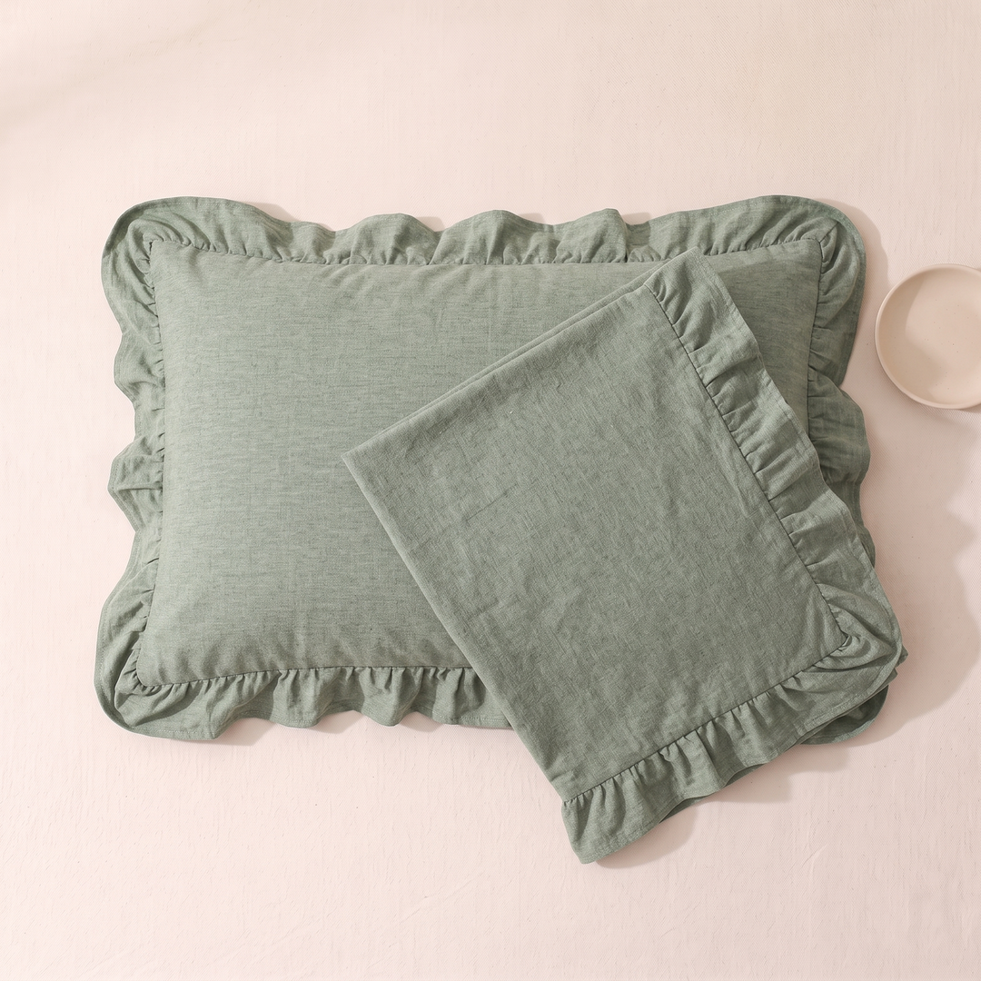 Cotton Pillowcases – Ruffled Plaid, Set of 2 in Sage – overlapping pair on pale pink surface beside a small bowl