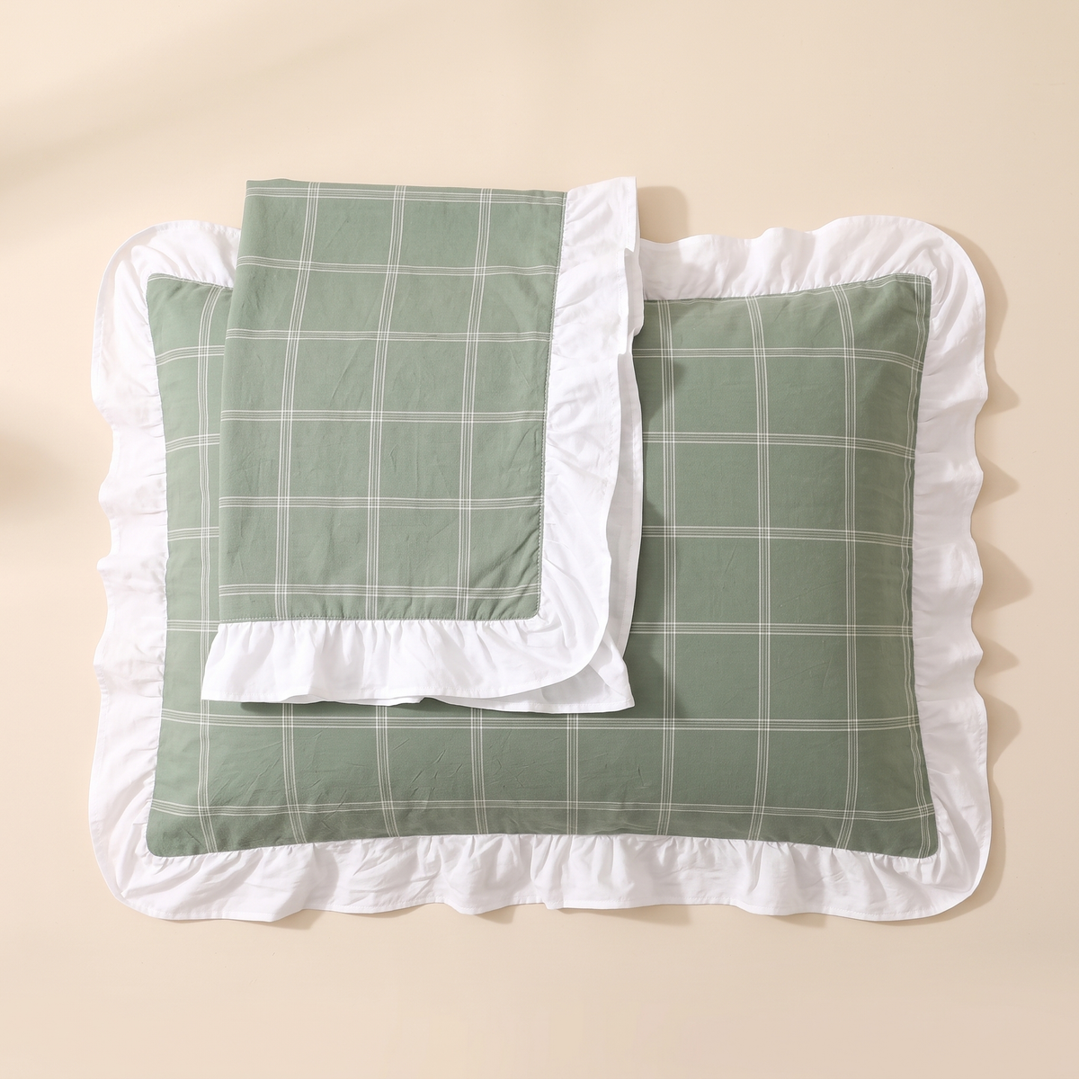 Cotton Pillowcases – Ruffled Plaid, Set of 2 in Green Grid – two stacked flat on a beige surface, overhead view