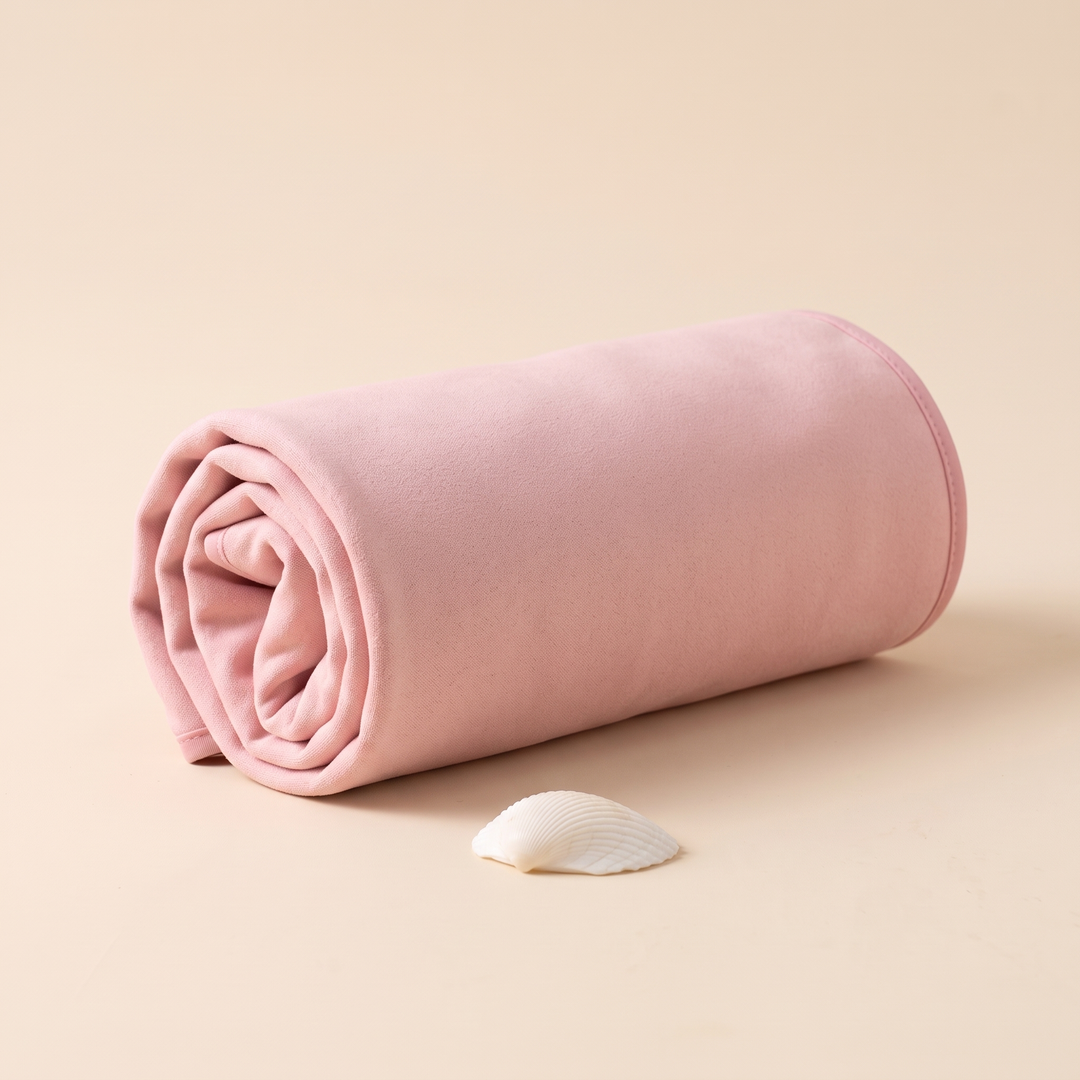 Sand-Free Beach Towel – Quick-Dry in Light Pink – loose roll lying sideways with a small shell in front