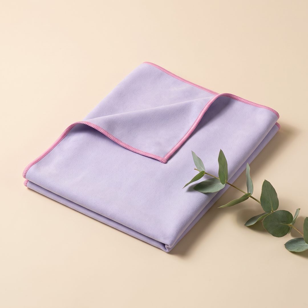 Sand-Free Beach Towel – Quick-Dry in Lilac – beside a eucalyptus sprig on a cream surface