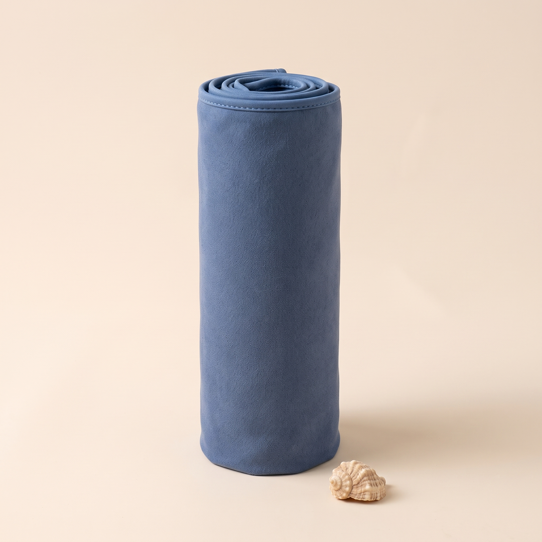 Sand-Free Beach Towel – Quick-Dry in Navy Blue – standing upright on end beside a small seashell