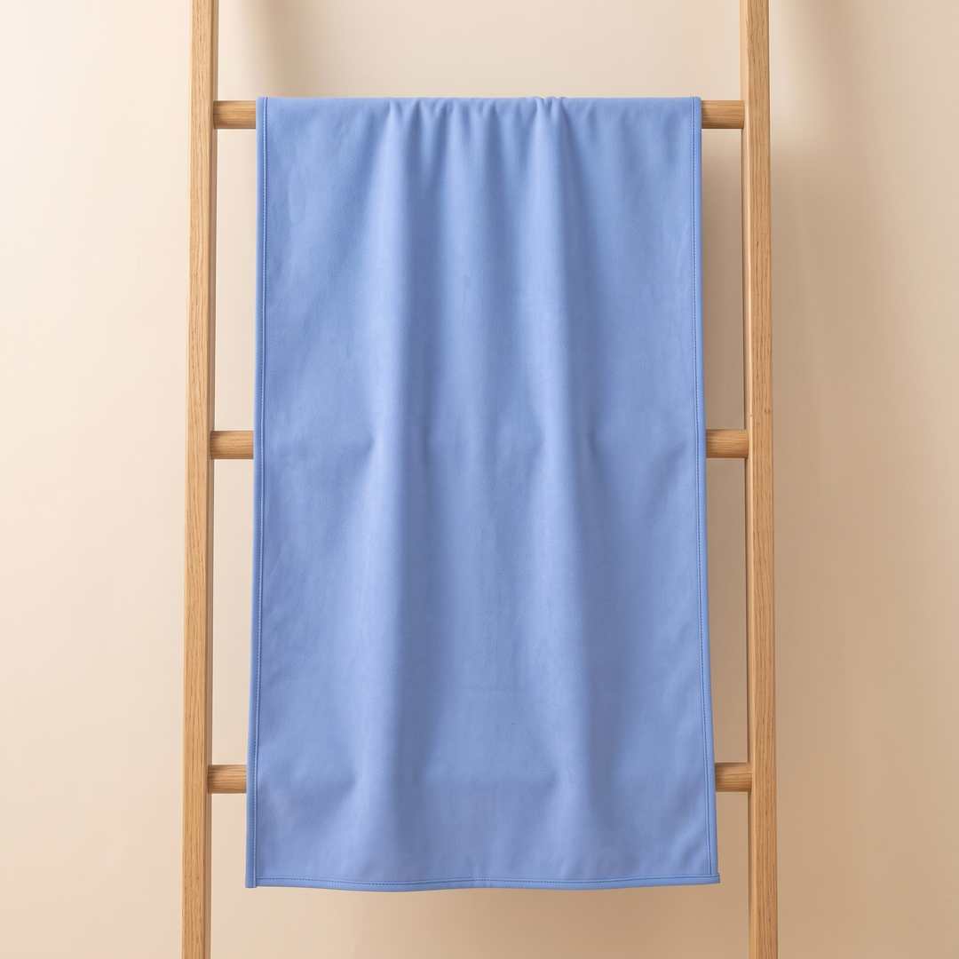 Sand-Free Beach Towel – Quick-Dry in Periwinkle Blue – hanging over a wooden ladder rung against a beige wall