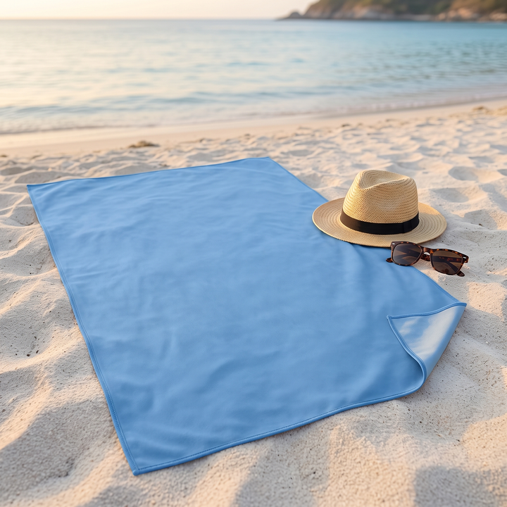 Sand-Free Beach Towel – Quick-Dry in Blue – spread flat on sand beside a straw hat and sunglasses