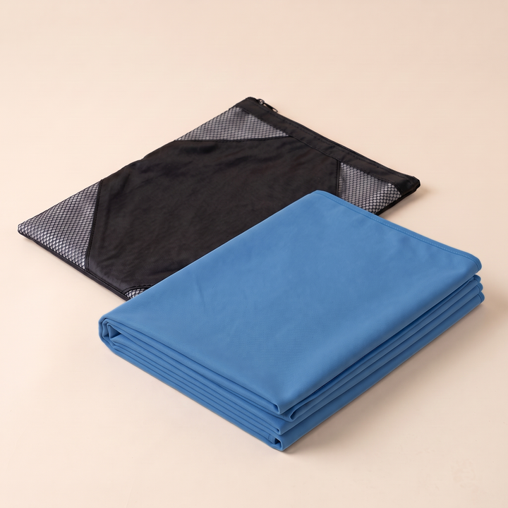 Sand-Free Beach Towel – Quick-Dry in Blue – folded neatly beside a black mesh zip bag on a peach background