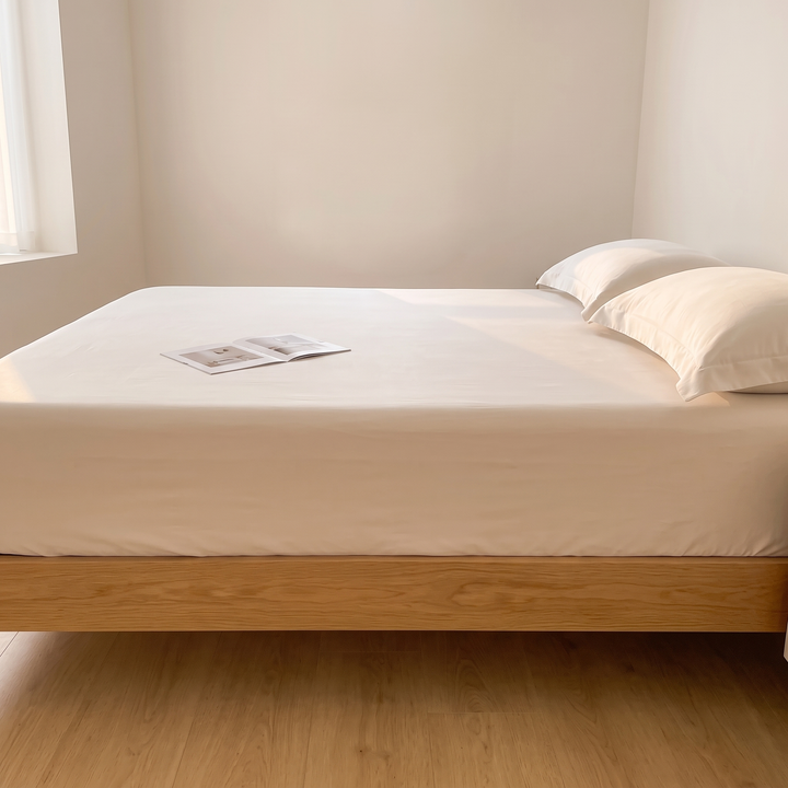Sateen Fitted Sheet Set with 2 Pillowcases in Oatmeal – straight-on side view with an open magazine on the mattress