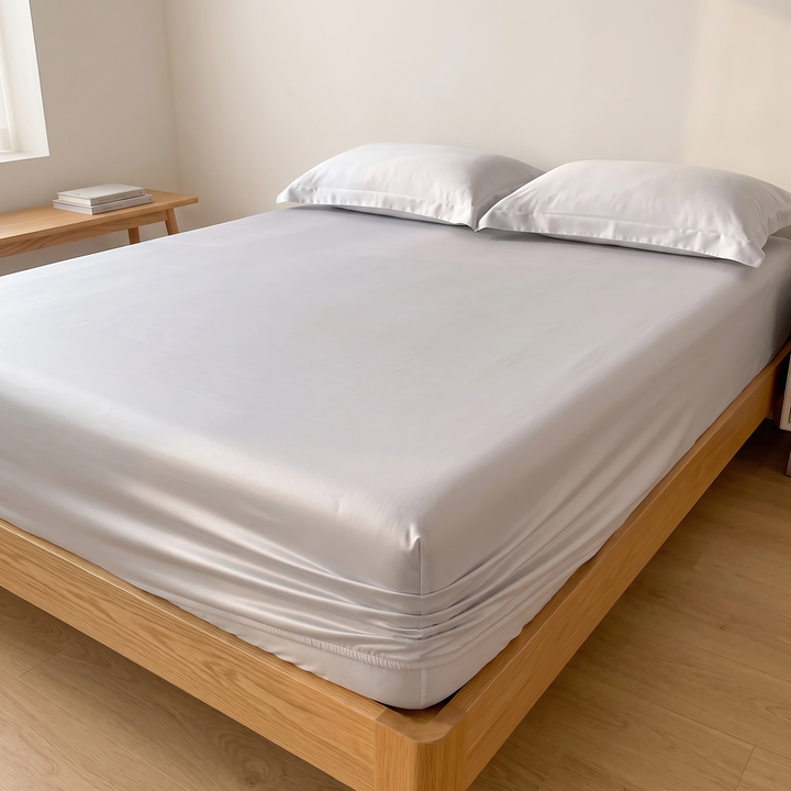 Sateen Fitted Sheet Set with 2 Pillowcases in Silver – high view across mattress toward pillows and stacked books