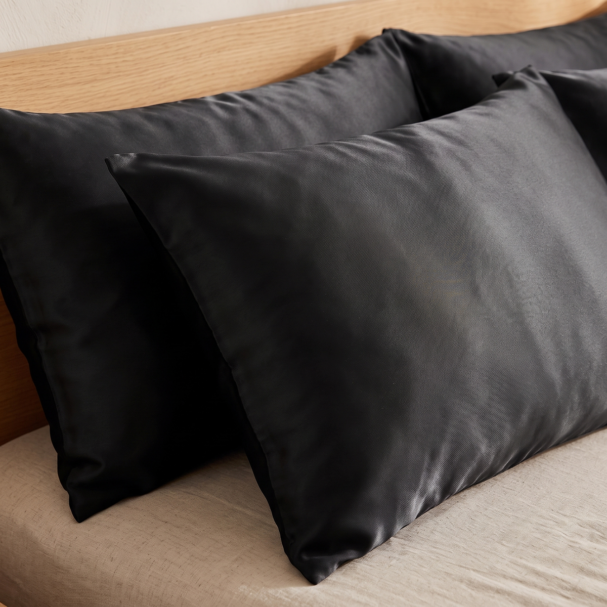 Black satin pillowcases on a made bed
