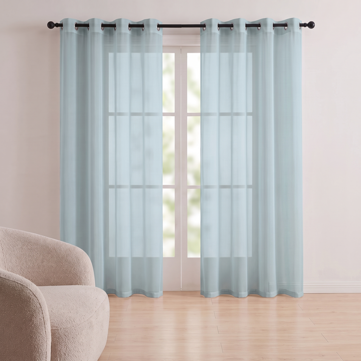 Sheer Voile Curtain Panel – Grommet Top in Aqua – with a beige textured armchair on light wood flooring