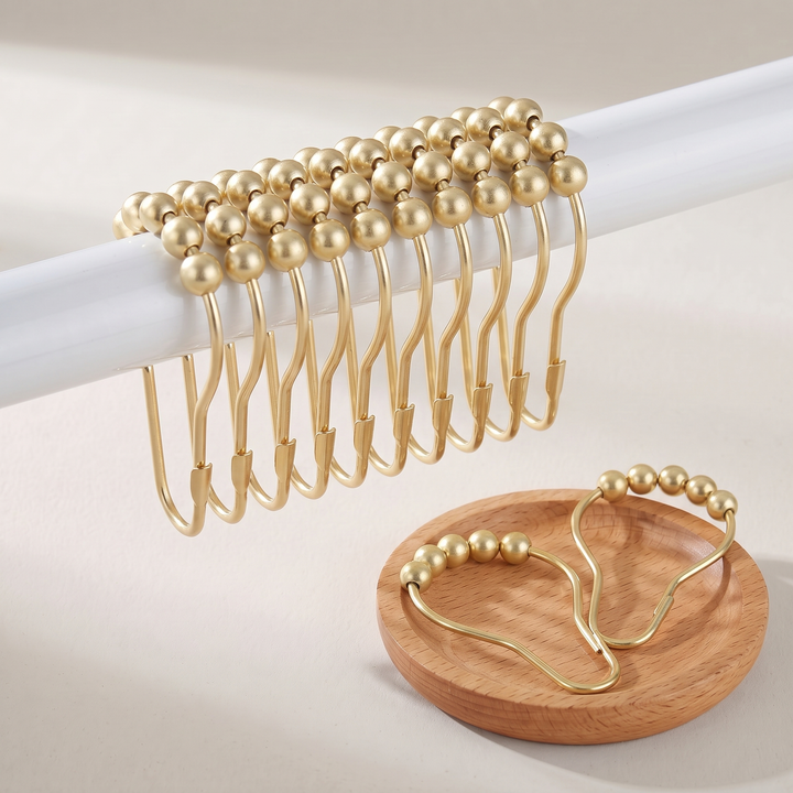 Shower Curtain Hooks – Set of 12, Roller Ball in Gold – on a white rod with a pair in a wooden dish