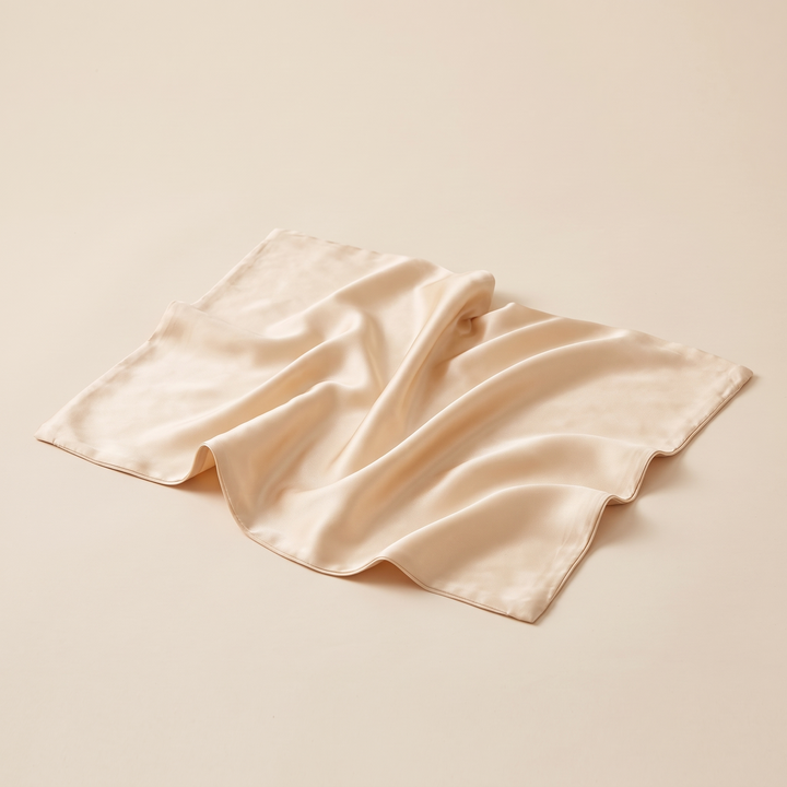 Silk Pillowcase – 19 Momme in Champagne – loosely rumpled with soft folds on a plain beige surface