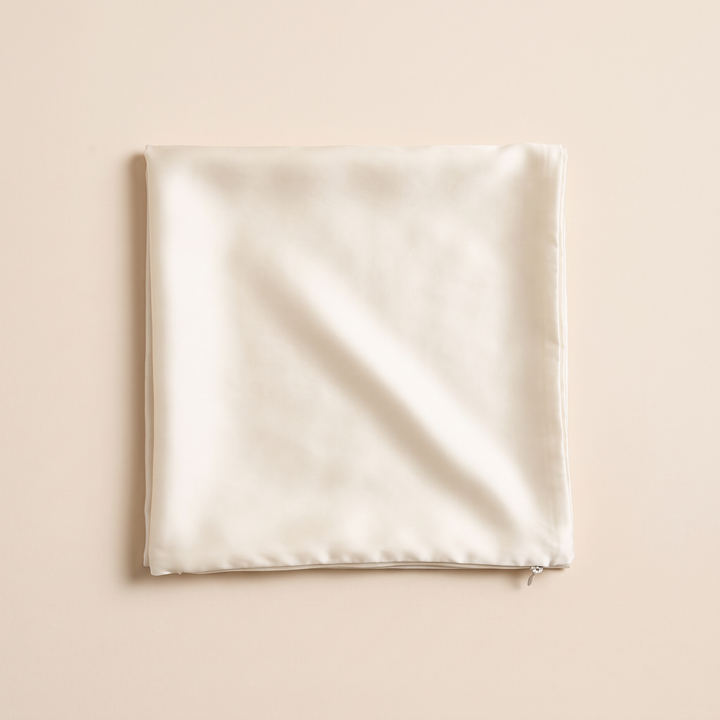 Silk Pillowcase – 19 Momme in Cream – folded square with a soft diagonal crease on a peach backdrop
