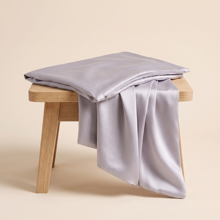 Silk Pillowcase – 19 Momme in Lilac – draped over a small oak stool with one end hanging down