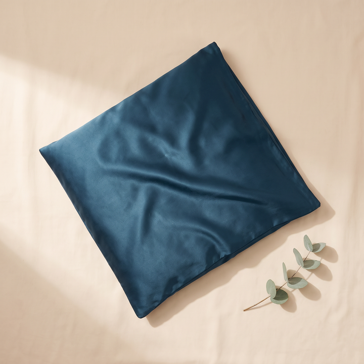 Silk Pillowcase – 19 Momme in Peacock Blue – beside a eucalyptus sprig on a sunlit cream sheet