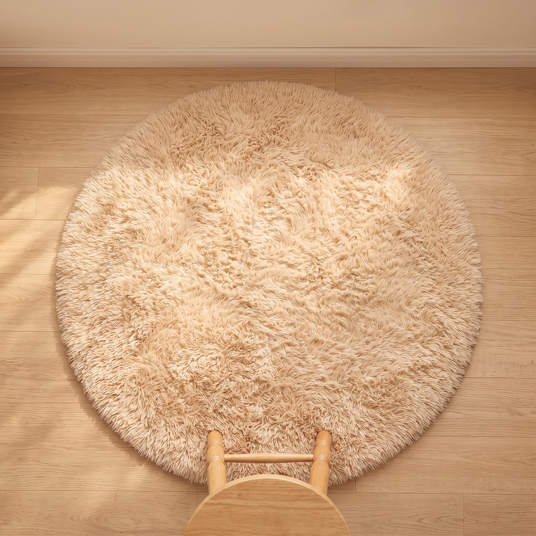 Small Round Shag Rug in Beige – overhead view on a wood floor with a wooden stool at the edge