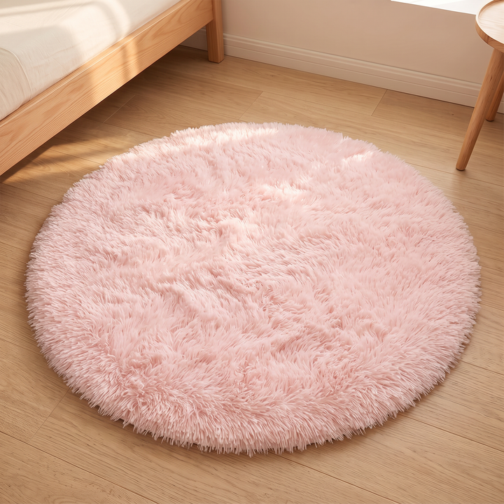 Small Round Shag Rug in Light Pink – centered on plank flooring with sunlight glowing across the pile