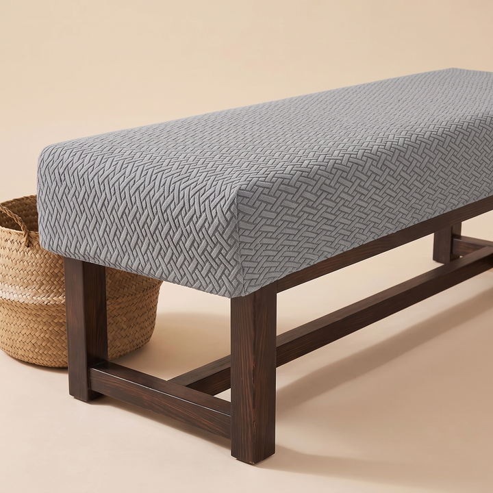 Stretch Bench Seat Cover – Jacquard in Gray – styled beside a woven straw basket, seen from a low corner angle