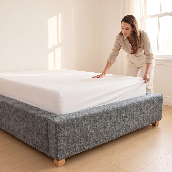 Stretch Box Spring Cover in Gray – side view of woman tucking white sheet onto mattress
