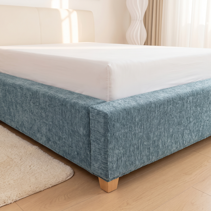 Stretch Box Spring Cover in Aqua – corner view with cream headboard and sheer curtains behind
