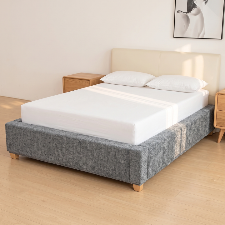 Stretch Box Spring Cover in Gray – angled full bed view beside wooden nightstands in sunlit room
