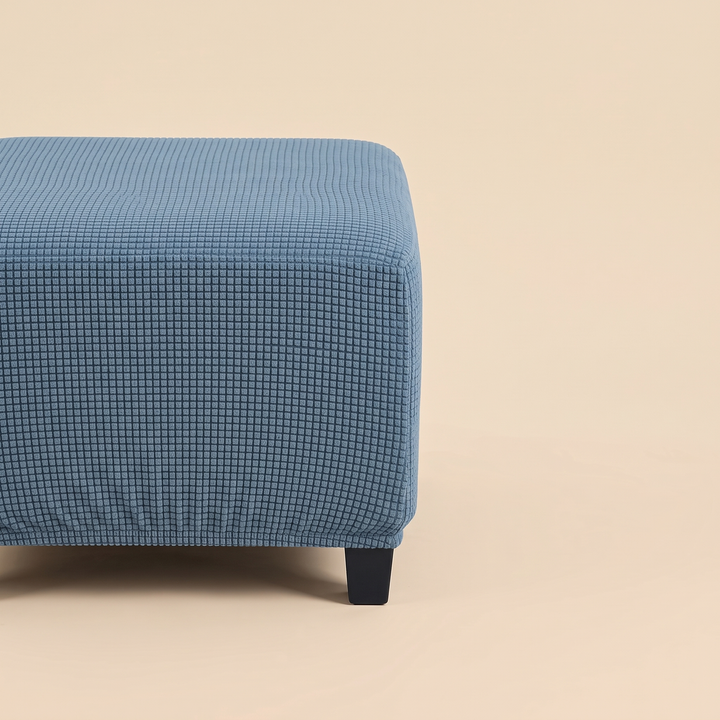 Stretch Ottoman Cover in Blue – partial side view showing a single dark leg and elastic hem