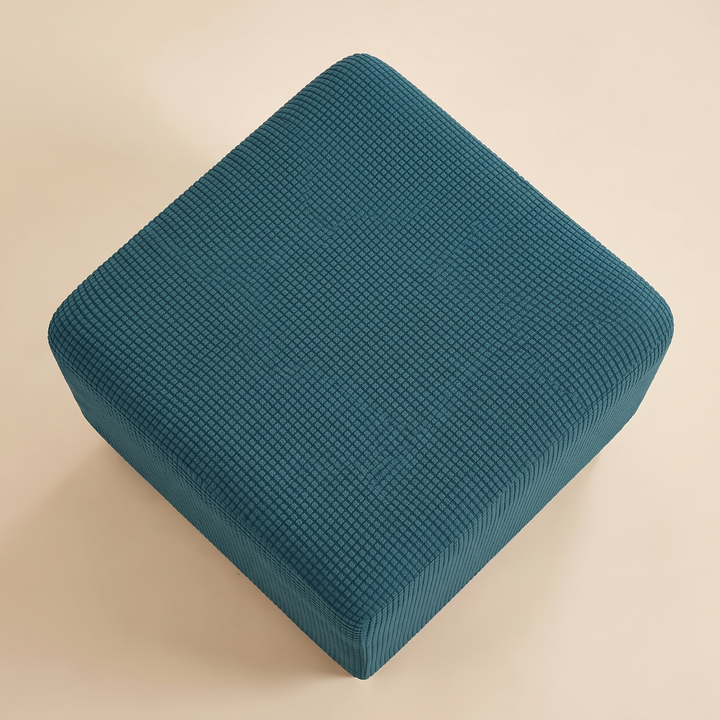 Stretch Ottoman Cover in Dark Teal – overhead view turned diagonally with one corner pointing toward the camera