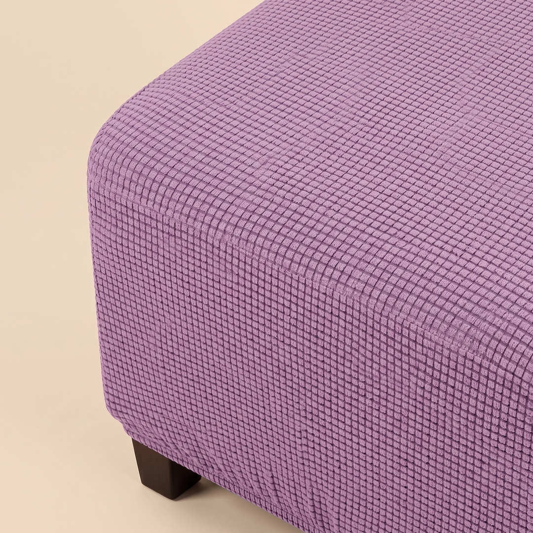 Stretch Ottoman Cover in Lavender – tightly cropped rounded corner seen from above, one foot visible