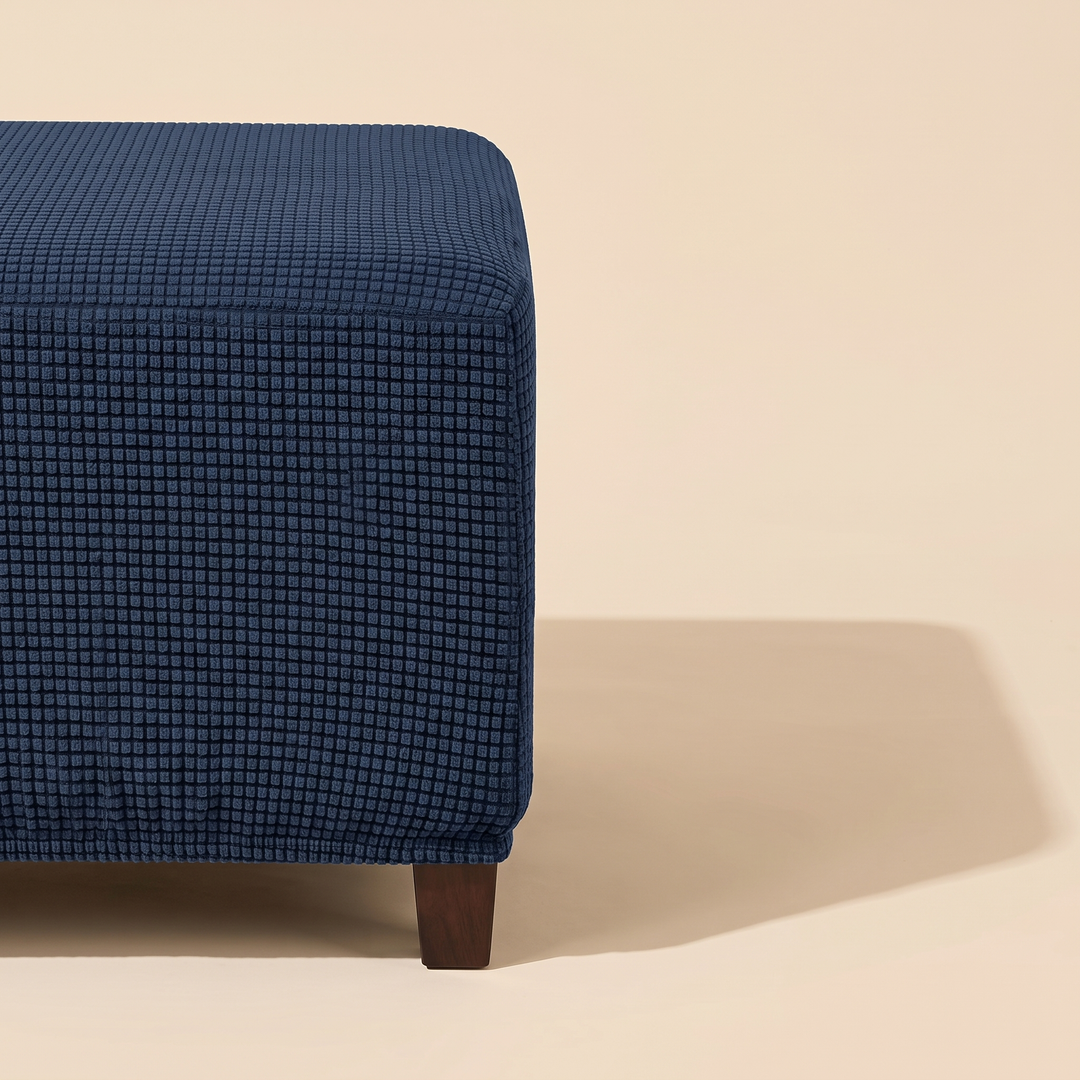 Stretch Ottoman Cover in Navy Blue – cropped at left edge with long angular floor shadow