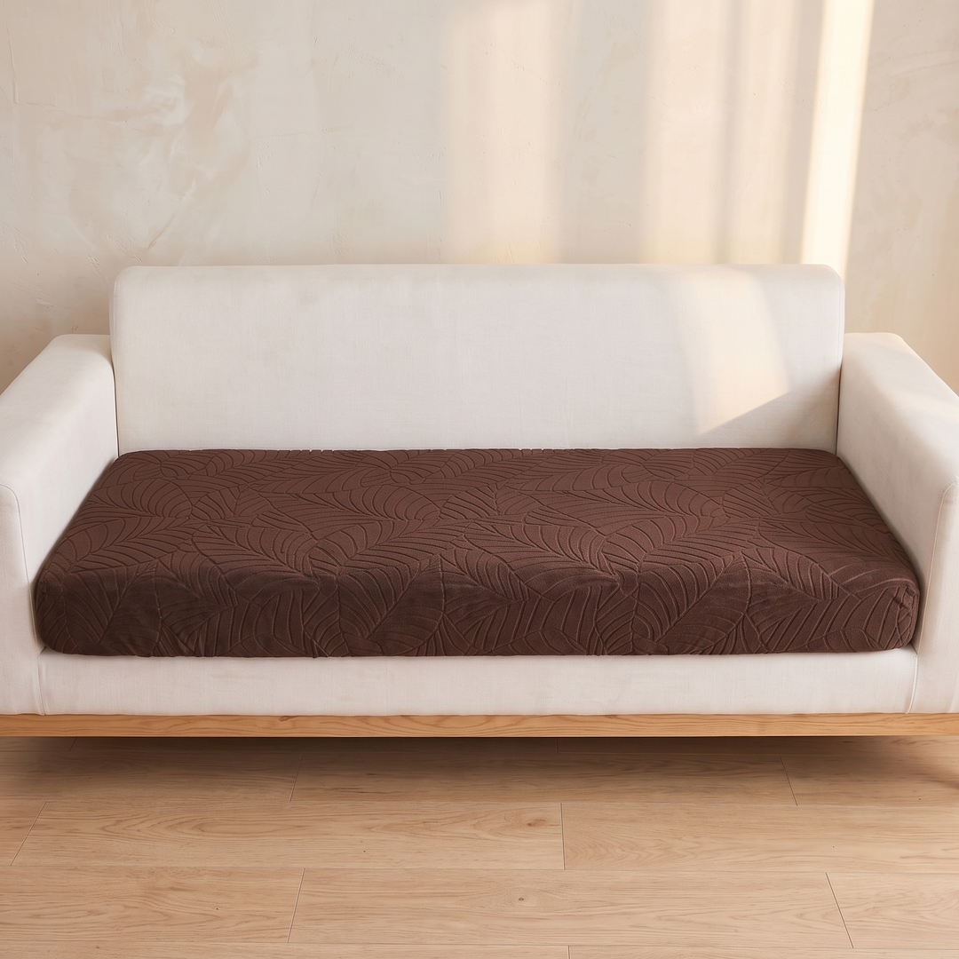 Stretch Couch Cushion Cover – Leaf Jacquard in Dark Brown – straight-on front view on a white sofa by sunlit wall