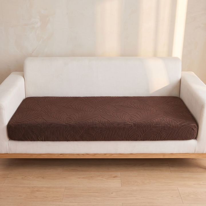 Stretch Couch Cushion Cover – Leaf Jacquard in Dark Brown – straight-on front view on a white sofa by sunlit wall