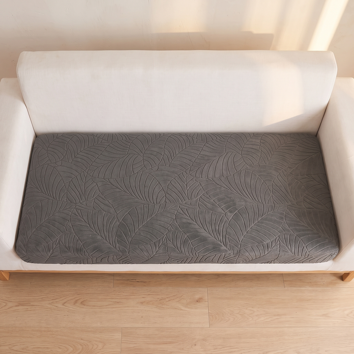 Stretch Couch Cushion Cover – Leaf Jacquard in Dark Gray – top-down view on a cream sofa above a light wood floor
