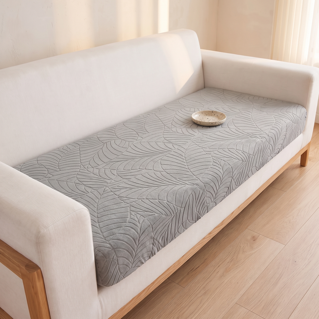 Stretch Couch Cushion Cover – Leaf Jacquard in Light Gray – angled high view with small speckled dish on the seat