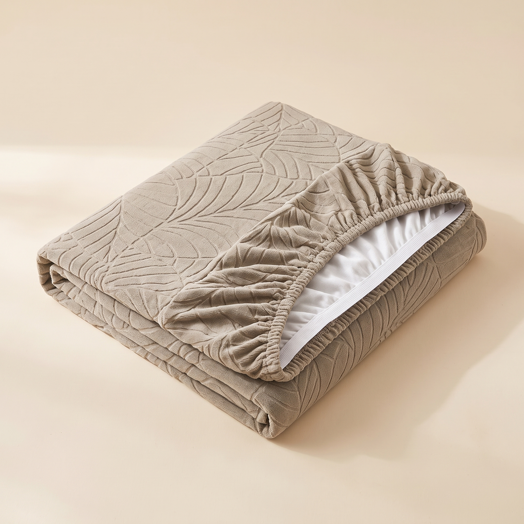 Stretch Couch Cushion Cover – Leaf Jacquard in Beige – folded on a plain surface with elastic hem and white lining visible