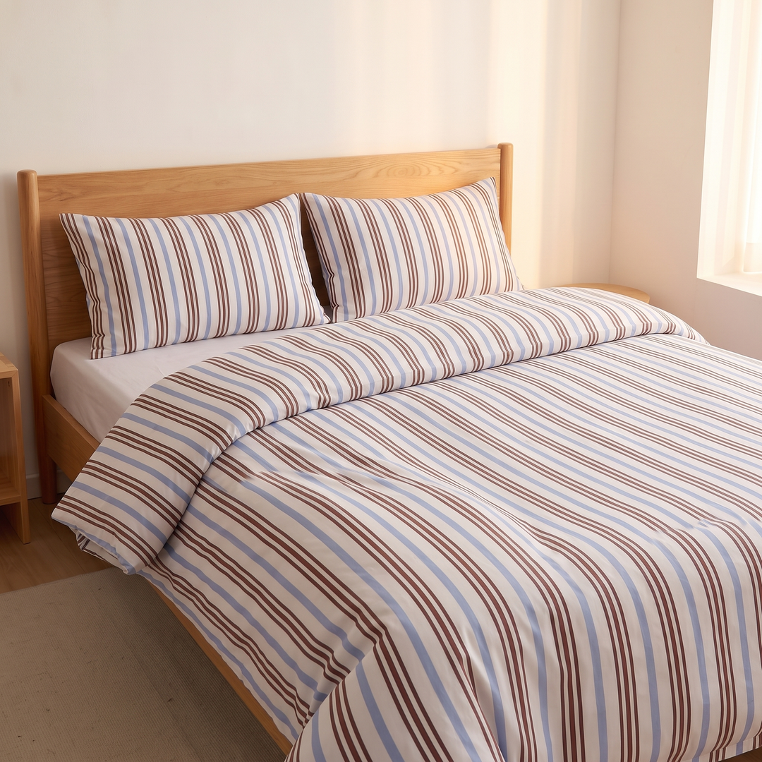 Striped Cotton Duvet Cover Set in Blue and Brown Stripe – three-quarter view with matching pillows beside a sunlit window
