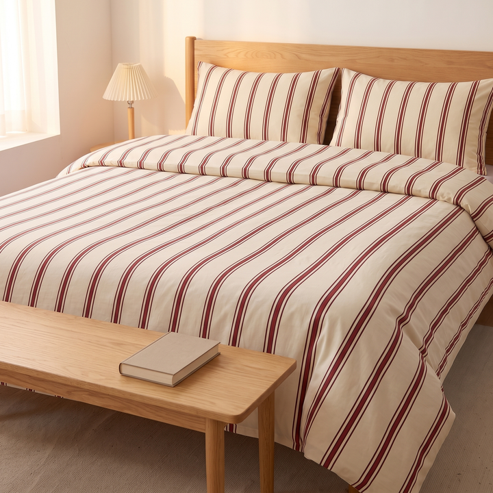 Striped Cotton Duvet Cover Set in Burgundy Pinstripe – bed seen past a wooden bench with a closed book