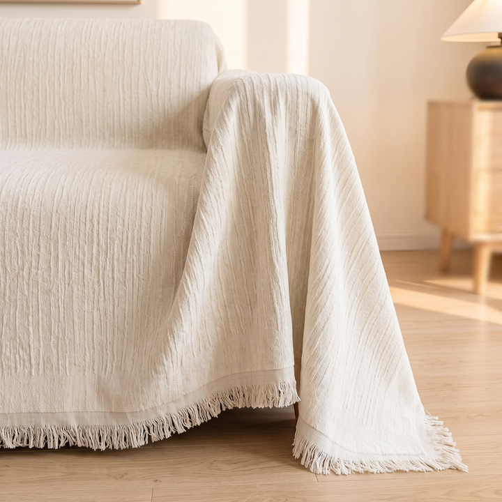 Striped Chenille Couch Cover with Fringe in Cream – covering a sofa arm beside a wooden side table