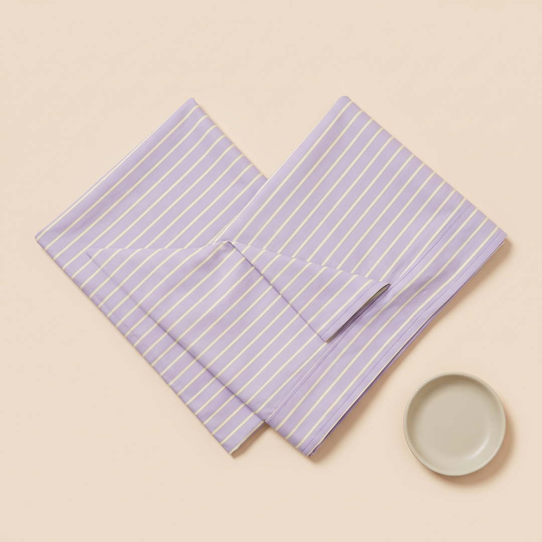 Striped Cotton Pillowcases – Set of 2 in Lavender Stripe – crossed diagonally with a small round ceramic dish beside them