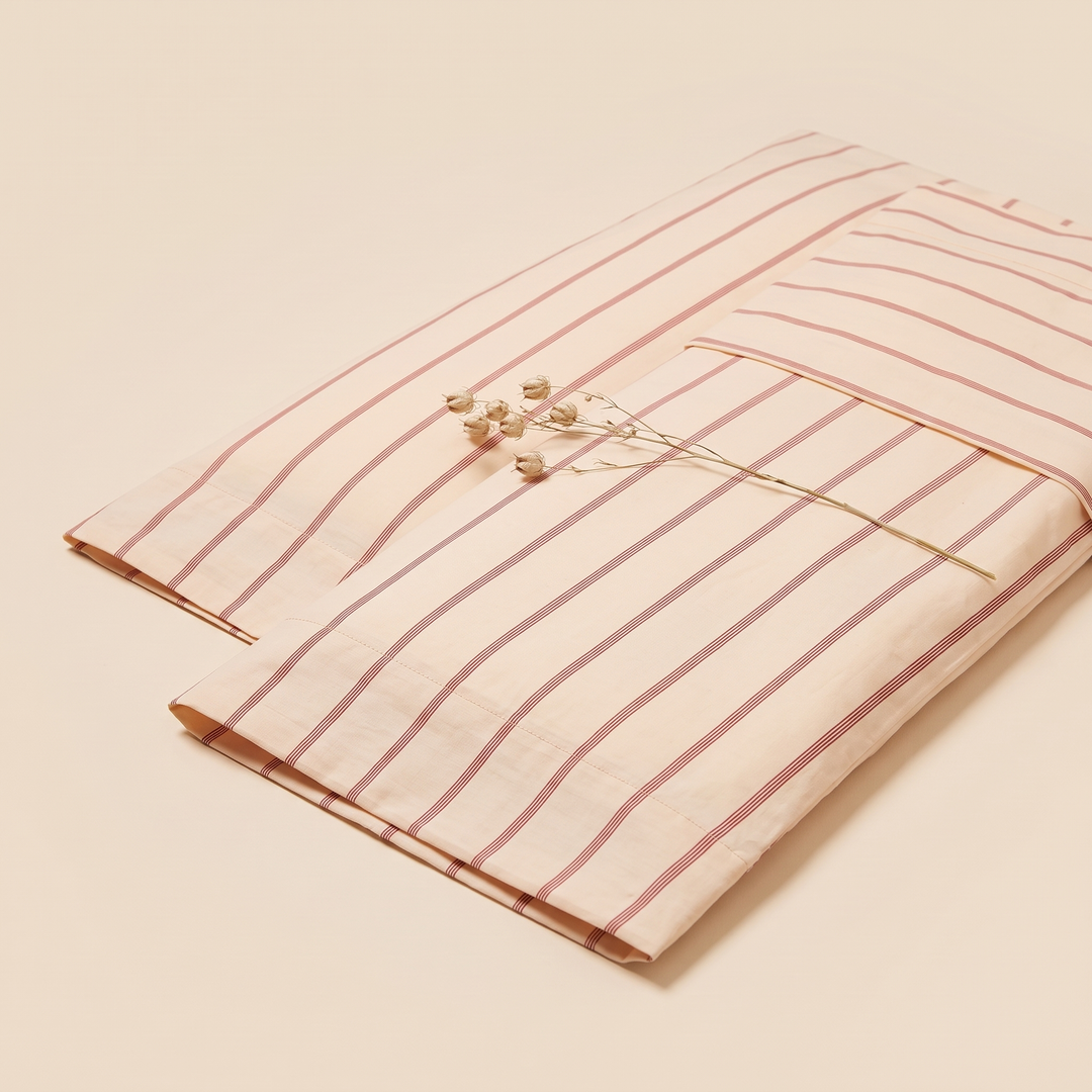 Striped Cotton Pillowcases – Set of 2 in Peach Stripe – angled view with dried seed pod stem across top