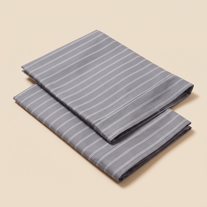 Striped Cotton Pillowcases – Set of 2 in Charcoal Stripe – two folded pillowcases stacked on a plain beige background