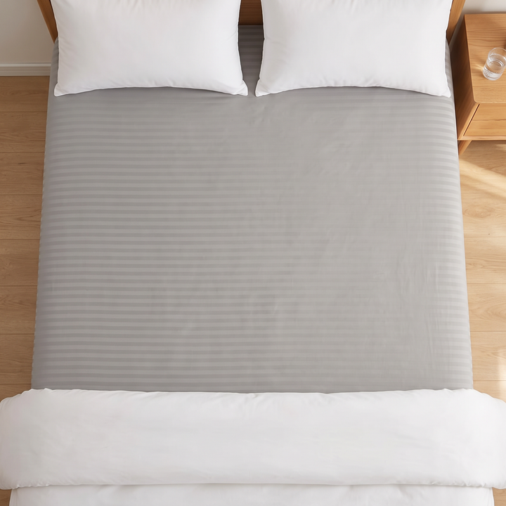 Striped Fitted Sheet – Tone-on-Tone in Gray – top-down view of bed beside nightstand with water glass