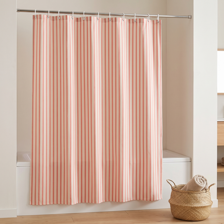 Striped Shower Curtain with Hooks in Coral Stripe – in a tub alcove beside a woven basket