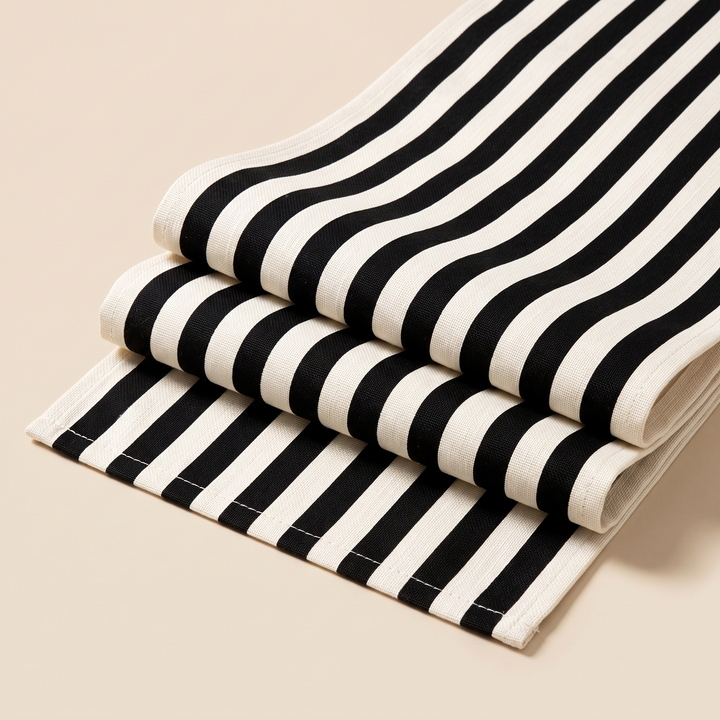 Striped Table Runner in Black Stripe – folded in layers on a plain beige background