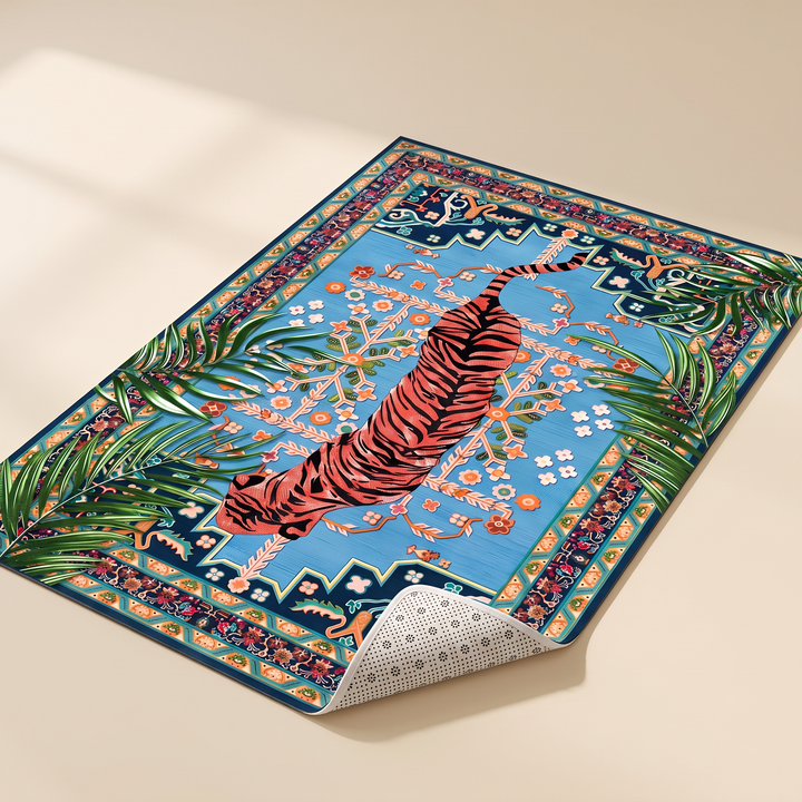Tiger Rug – Non-Slip in Blue – Persian – lying flat on a plain beige surface at an angle, with palm leaves overlapping the edges