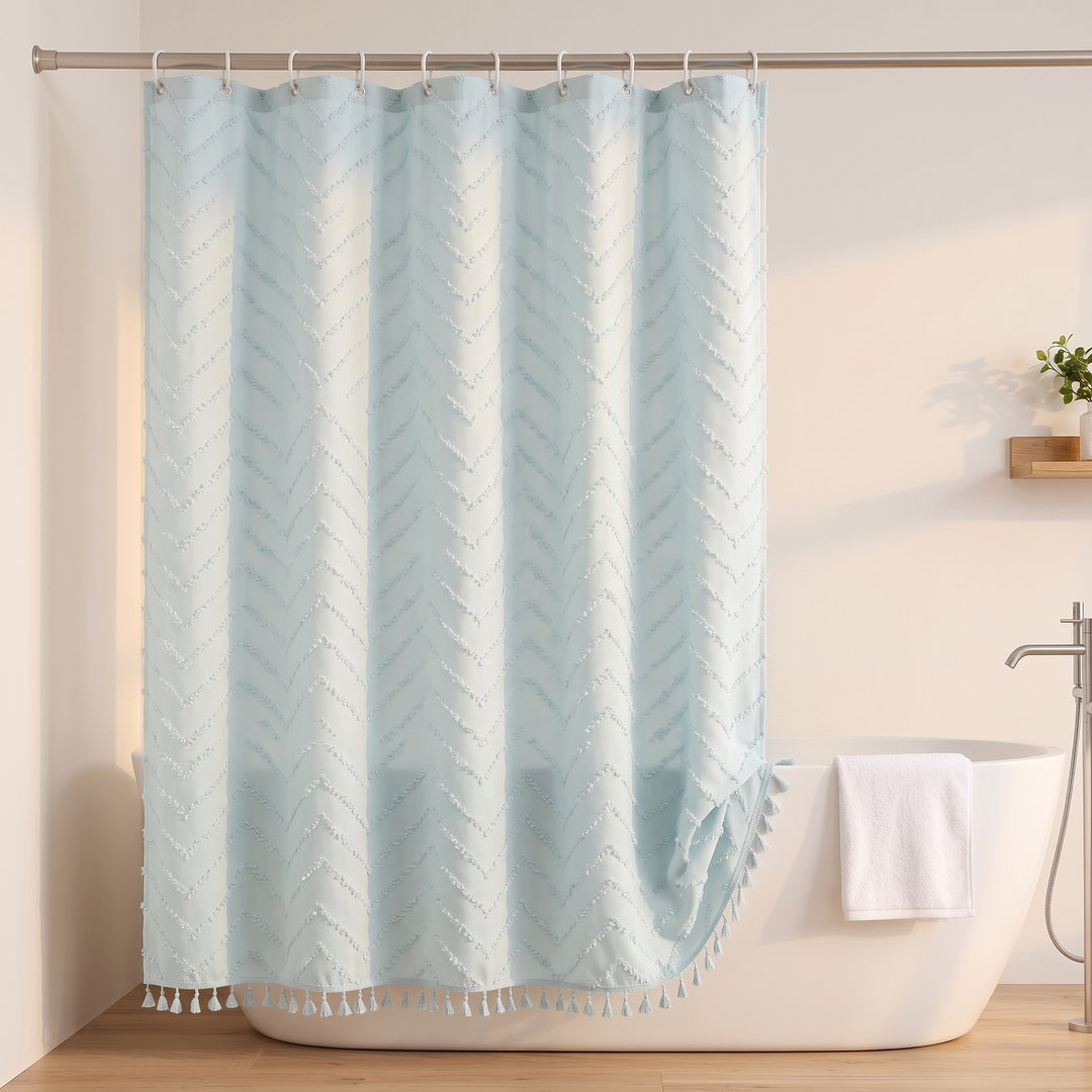 Boho Fabric Shower Curtain – Tufted, with Tassels in Light Blue Chevron – hanging beside a white towel and floor-mounted tub faucet