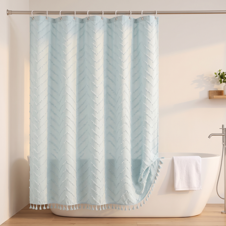 Boho Fabric Shower Curtain – Tufted, with Tassels in Light Blue Chevron – hanging beside a white towel and floor-mounted tub faucet