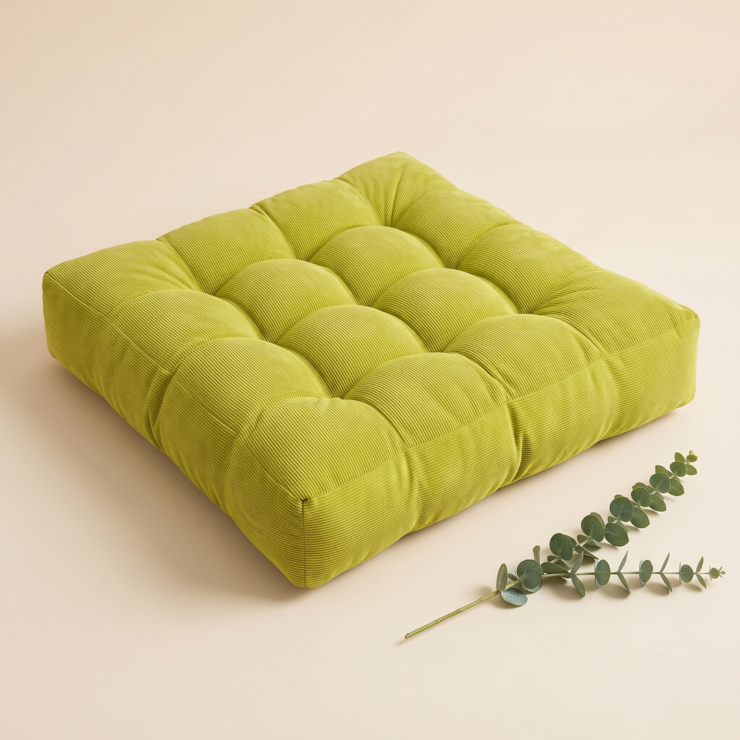 Tufted Floor Cushion – Square in Lime Green – with a eucalyptus sprig lying beside it