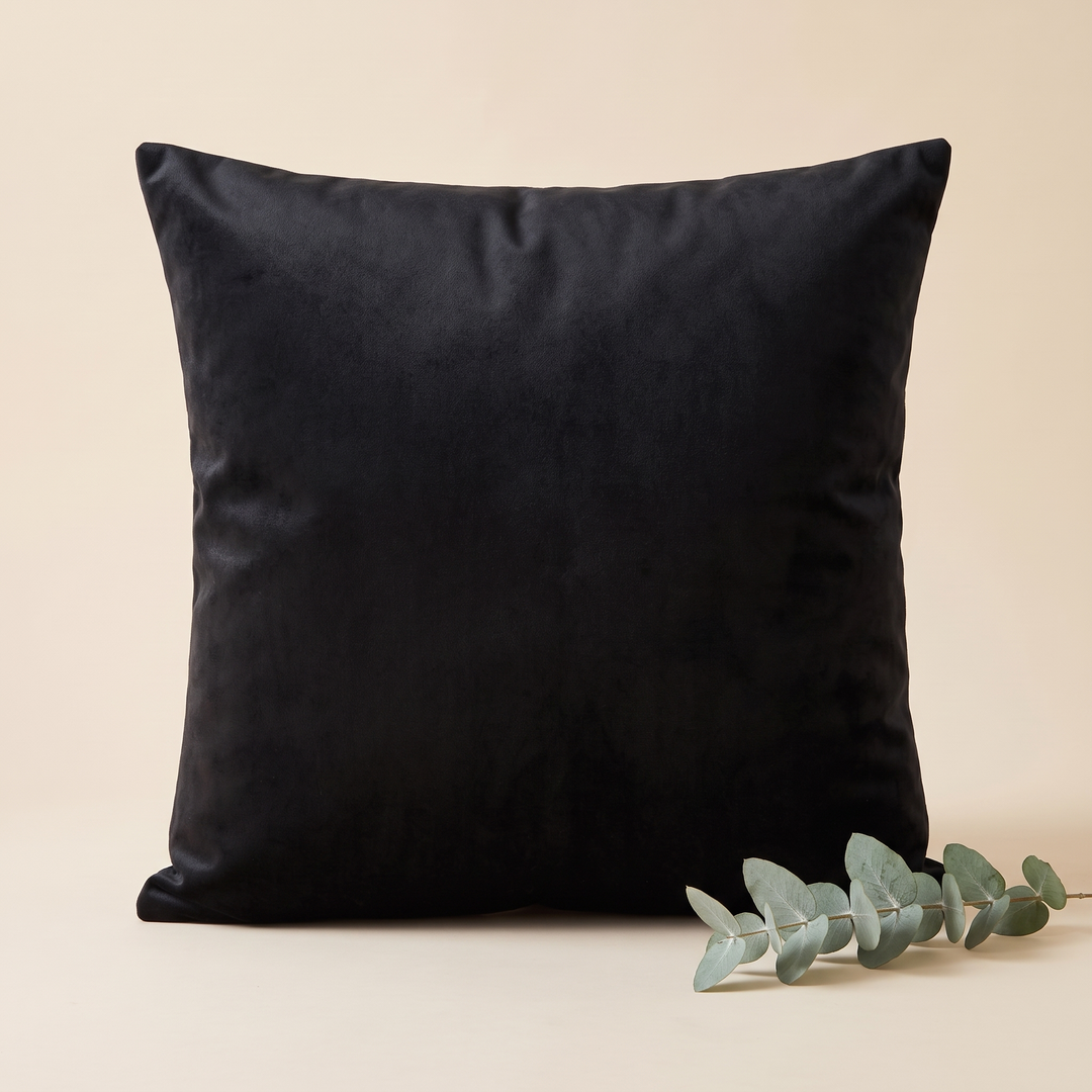 Velvet Pillow Cover in Black – with a eucalyptus sprig resting in front at lower right