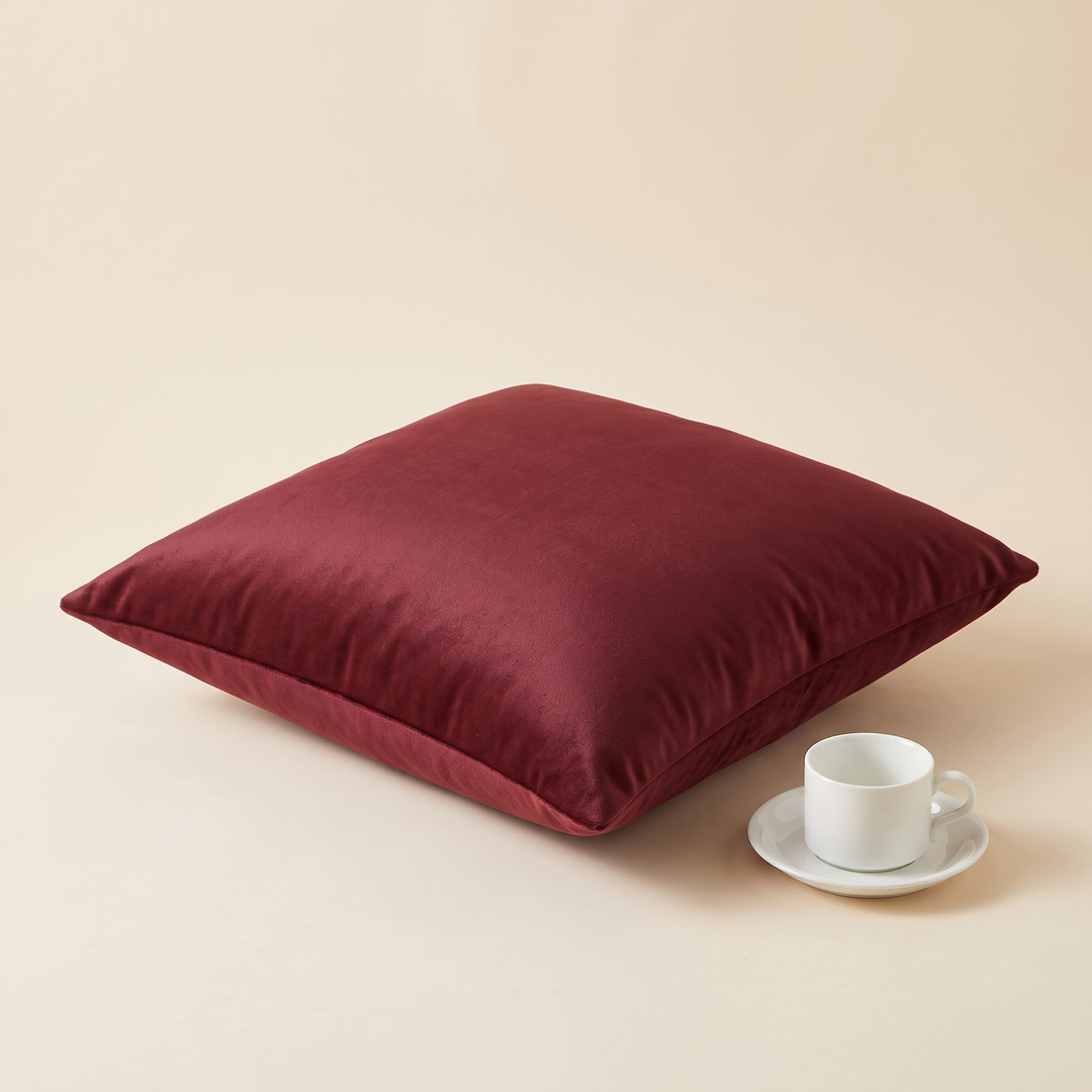 Velvet Pillow Cover in Burgundy – lying flat at an angle beside a white teacup and saucer