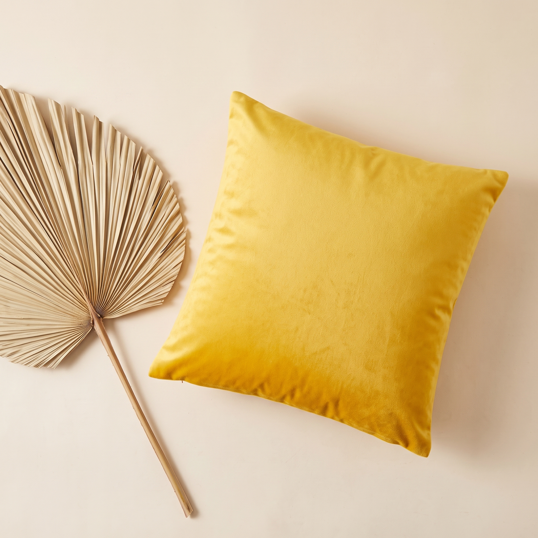 Velvet Pillow Cover in Golden Yellow – beside a dried pleated palm leaf, seen from above