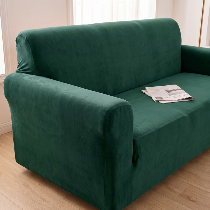 Velvet Stretch Sofa Cover in Dark Green – side angle showing backrest and arm with newspaper on seat