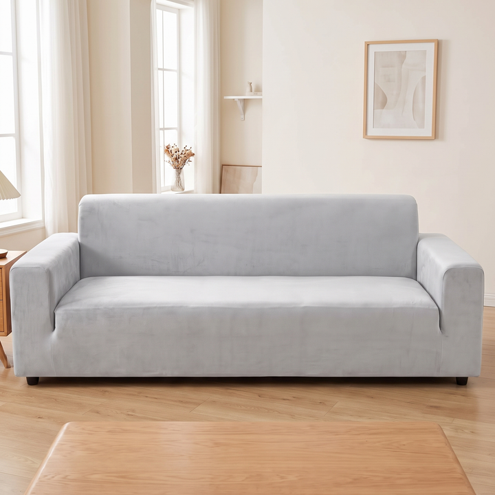 Velvet Stretch Sofa Cover in Light Gray – beneath framed art with wooden coffee table in foreground